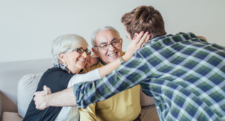 An elderly couple embracing a young man, depicting a heartwarming display of familial love, support, and connection across generations.