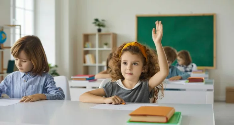 Young girl raising hand in classroom setting