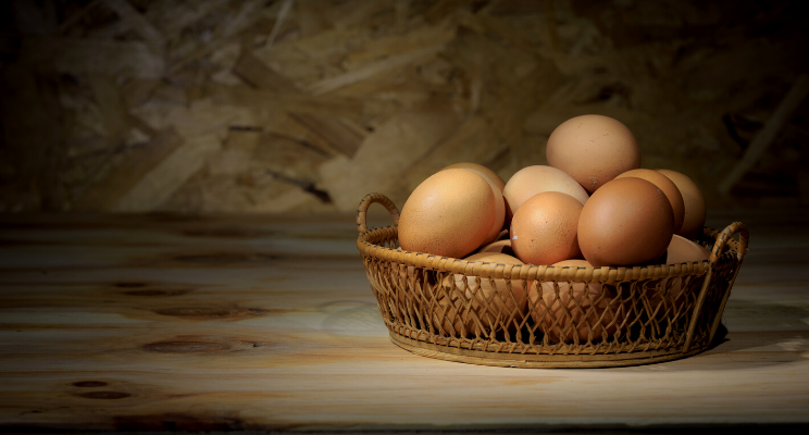 Eggs neatly arranged in a basket placed on a wooden table, representing freshness, simplicity, and the bounty of nature.