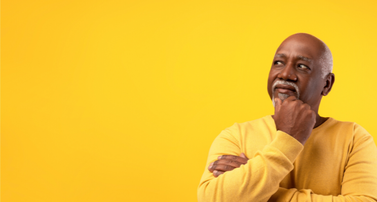 A man wearing a yellow sweatshirt in a contemplative pose, positioned against a matching yellow background, creating a visually cohesive and reflective composition.